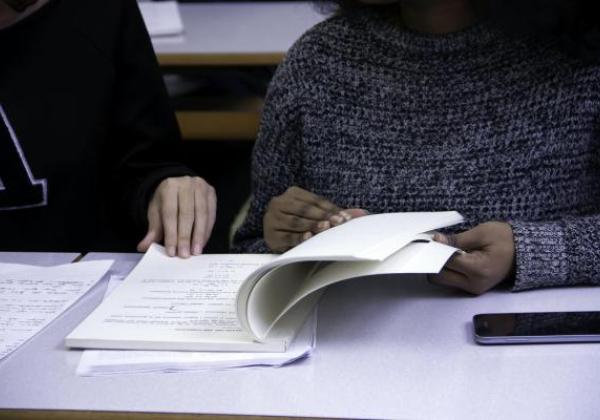 Hands turning pages of textbook.